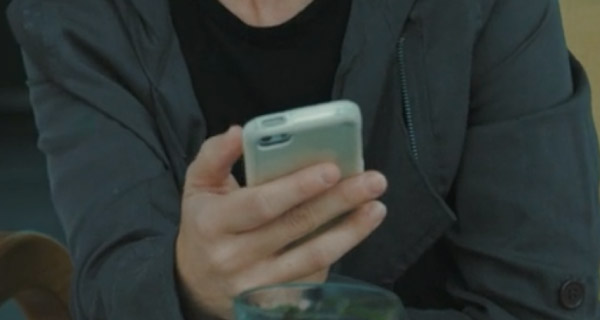 Blog Header of a person in a dark blue shirt and lighter blue jacket on their phone, presumably searching up how to contact a psychic medium.