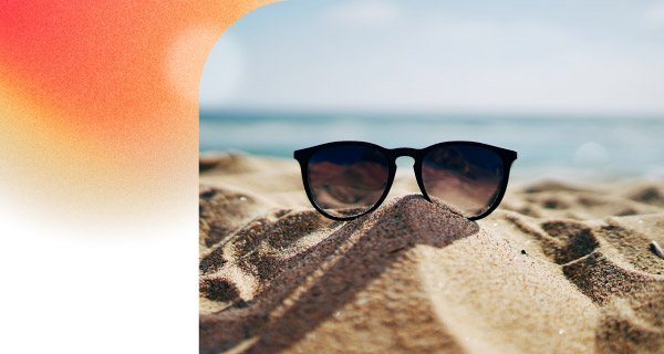 A close-up shot of some sunglasses, forgotten on the beach. The blue sky is visible in the background.